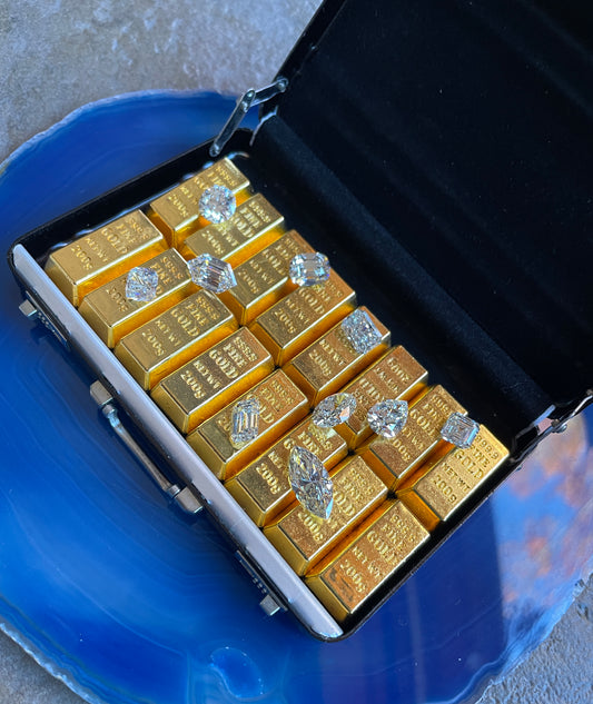 picture of a tiny suitcase filled with little gold bars and a bunch of lab created diamonds